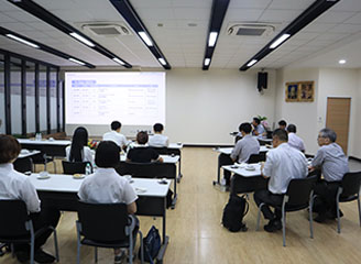 室内で事業概要の説明を受ける学生たち