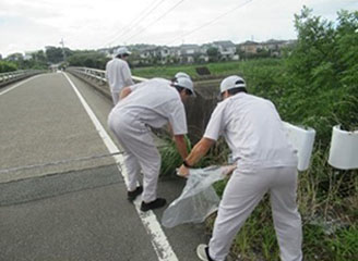 Employees cleaning up the area around the factory.