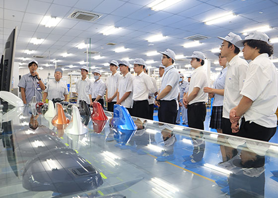 Employees explaining equipment to students on the factory floor.(1 of 2)