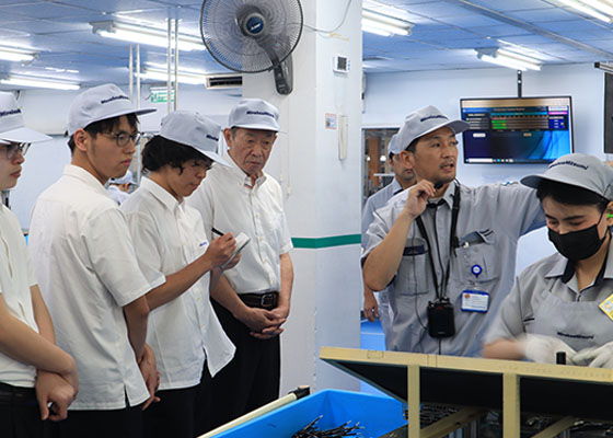Employees explaining equipment to students on the factory floor.(2 of 2)