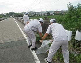 Employees cleaning up the area around the factory.