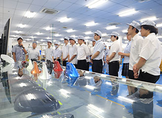 Employees explaining equipment to students on the factory floor.