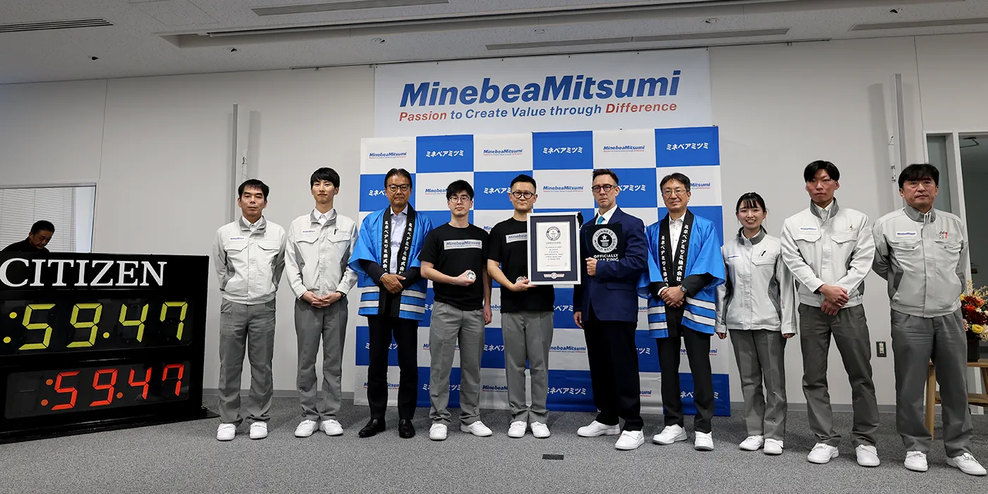 認定証の右手がギネスワールドレコーズ公式認定員ジャスティン・パターソン氏、左から3番目がミネベアミツミ 代表取締役 会長CEO 貝沼由久、プロジェクトチームのメンバーと